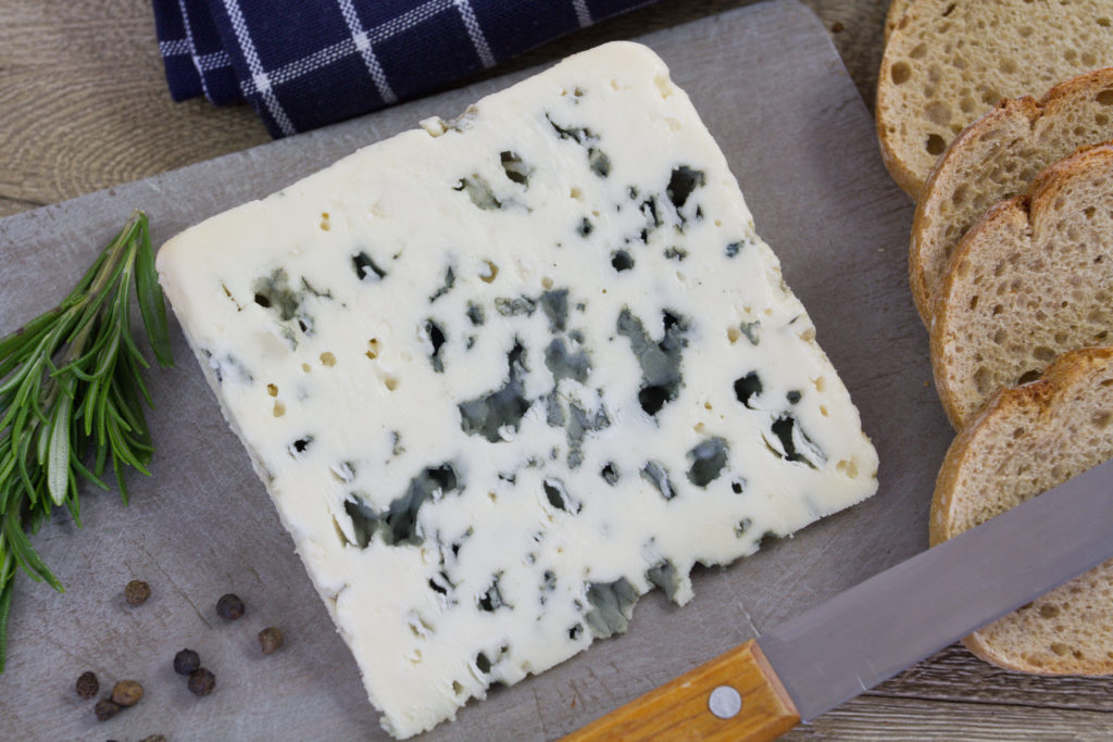 Wedge of blue cheese with a knife and bread
