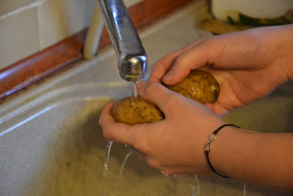 Washing potatoes in the sink to remove dirt. 