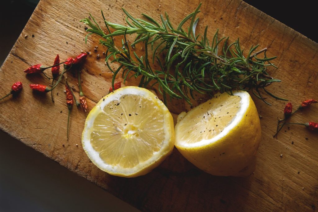 Lemons on a cutting board with herbs and spices. 