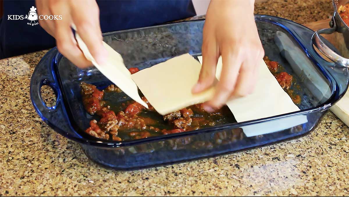 Add a layer of sauce and lasagna sheet to a baking dish