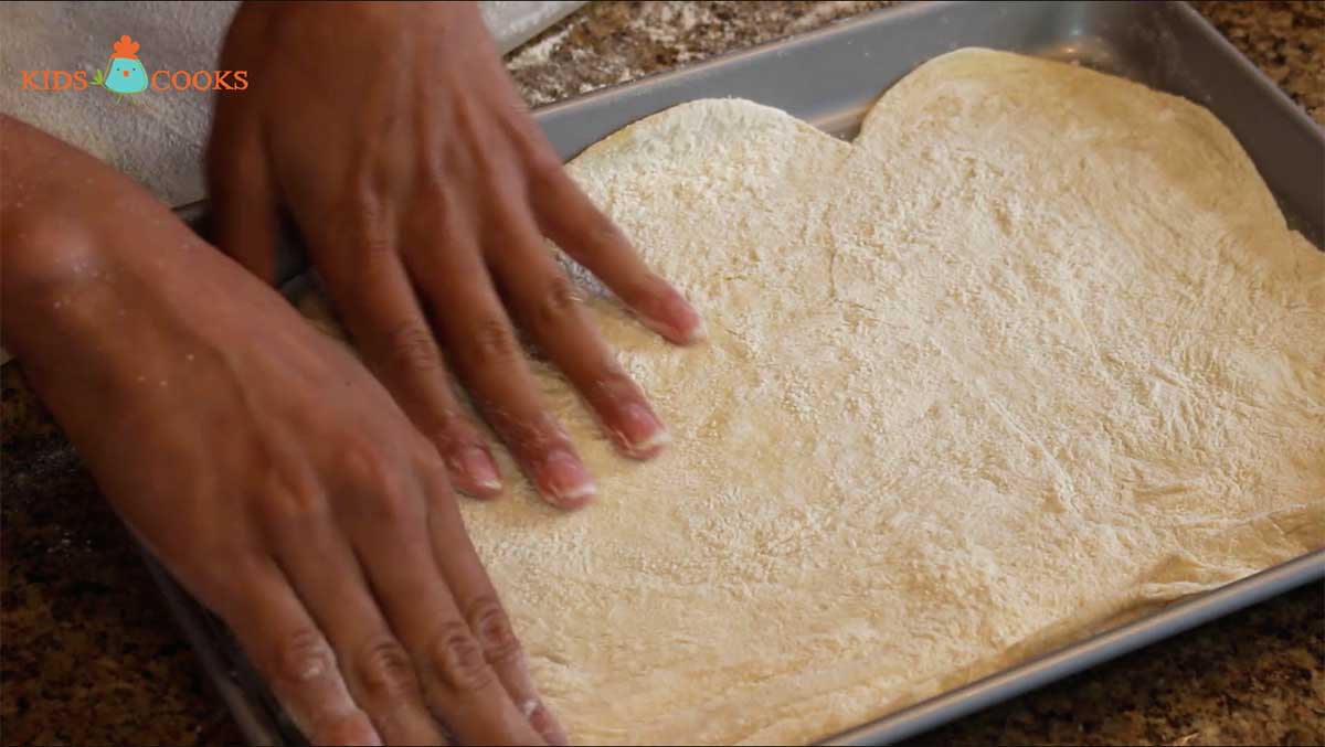Take half of the dough and shape it on an oiled baking sheet